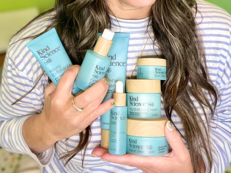 a woman with long hair holds 7 Kind Science skincare products