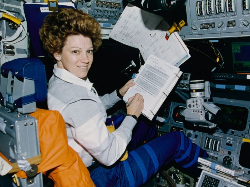 Eileen Collins looks at paperwork in commander's seat of Space Shuttle Atlantis