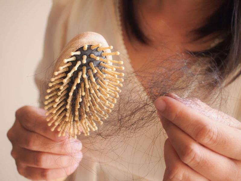 Woman holding clump of hair from brush