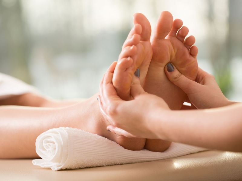 Masseuse performs foot massage
