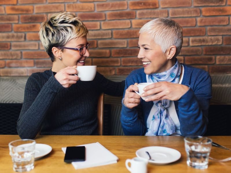 Two midlife women talking and drinking coffee at a table