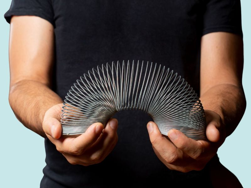 A person holds a metal slinky in their hands