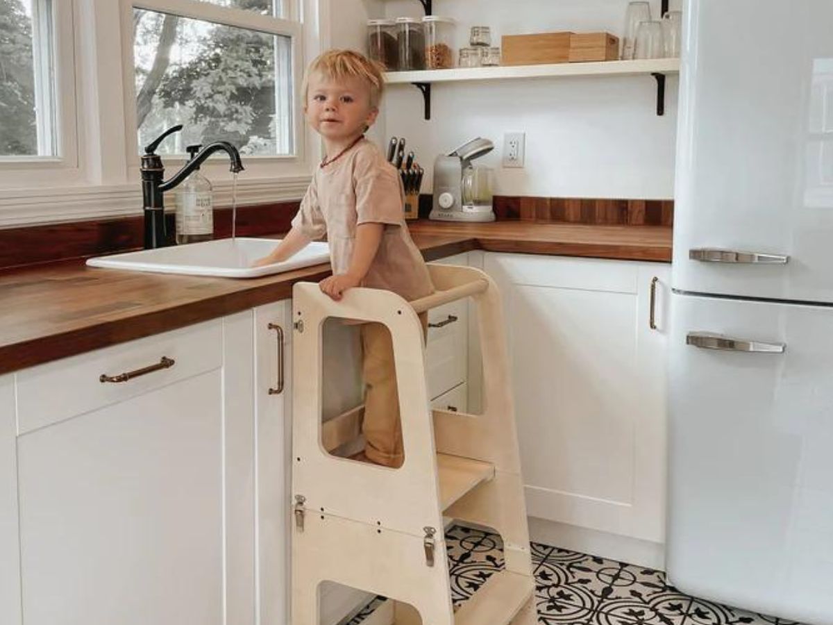A young boy standing at a kitchen sink using Piccalio's mini chef convertible helper tower