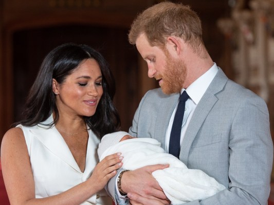 Meghan Markle (L) and Prince Harry holding their newborn son Archie at his christening