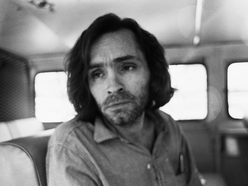 Black and white photo of a young Charles Manson sitting on a bus
