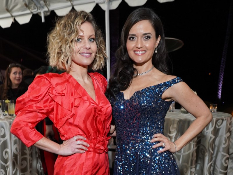 Candace Cameron bure (L) in red dress standing next to Danica McKellar, who is wearing a navy blue dress