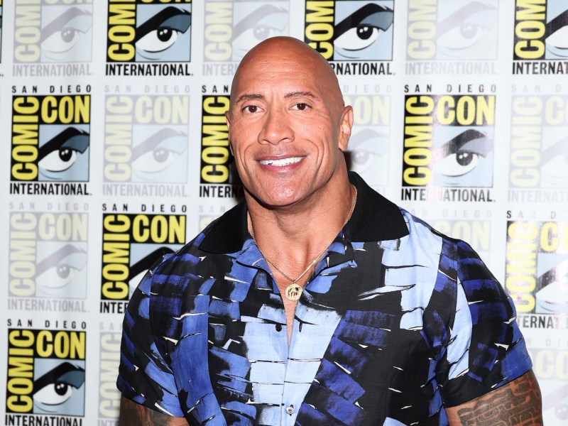 Dwayne Johnson smiling in a blue shirt at Comic Con