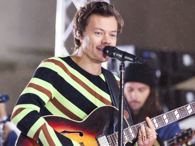 Harry Styles in a sweater playing on stage in May 2022