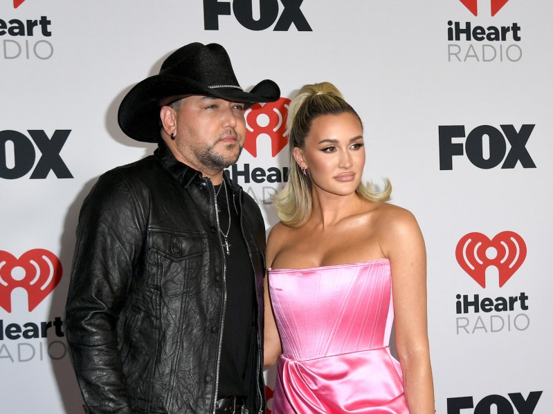 Jason Aldean in a black leather jacket with wife Brittany in a pink dress