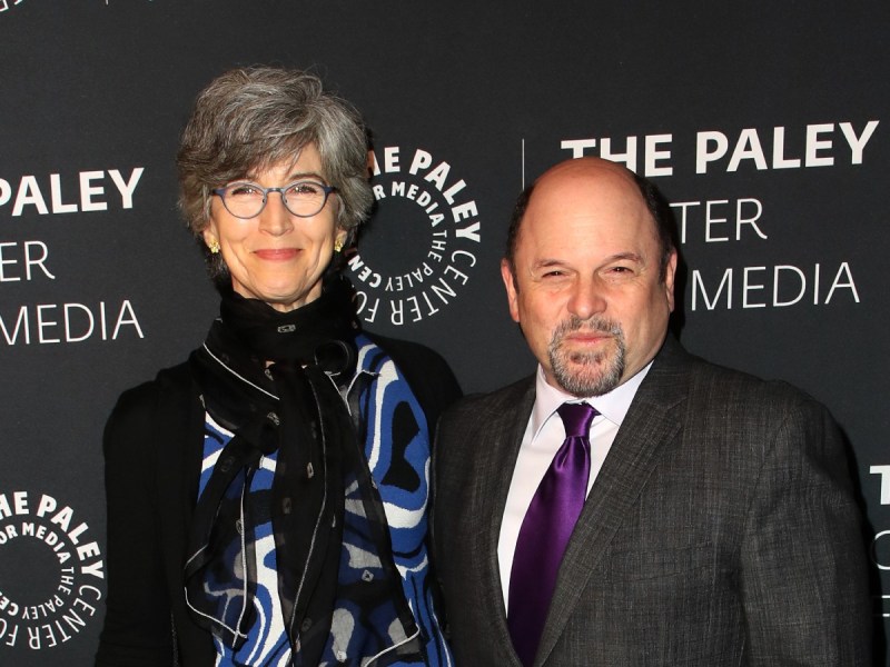 Jason Alexander (R) in charcoal suit and purple tie standing next to Daena E. Title, who is wearing a black and blue top