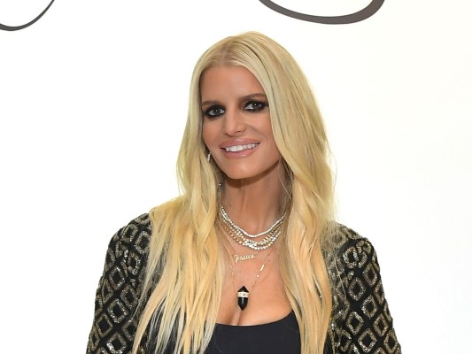 closeup of Jessica Simpson smiling in a black and gold outfit