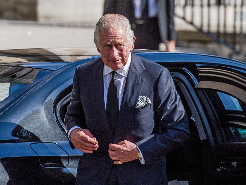 King Charles III exits a car in a navy suit