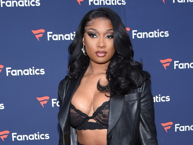 Megan Thee Stallion posing in a black lace top and black leather jacket