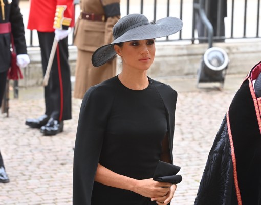 Meghan Markle in a black cape, dress, and hat at Queen Elizabeth's funeral