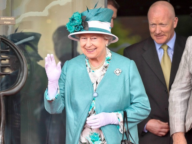 Queen Elizabeth smiling and waving in turquoise coat and matching hat