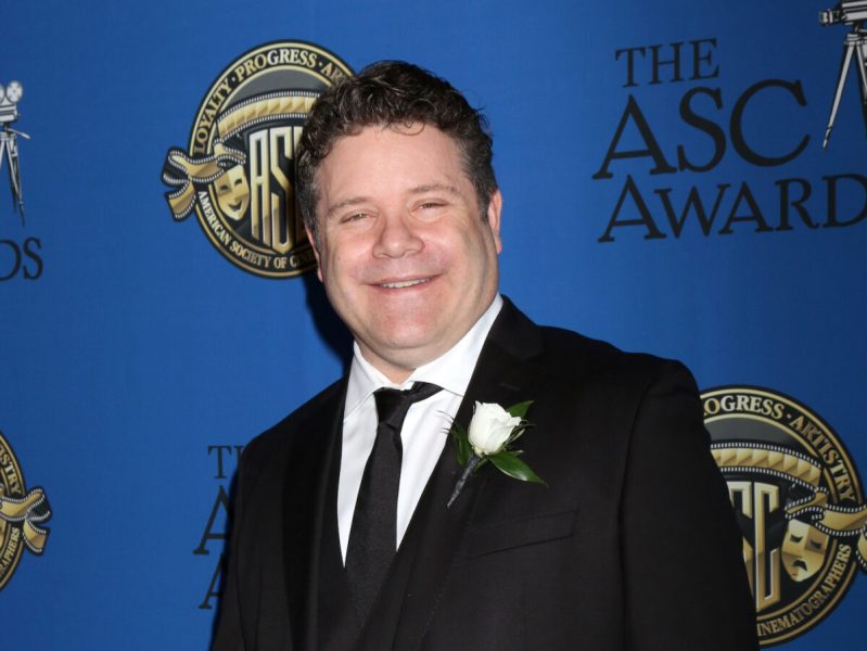 Sean Astin smiling in a black suit in 2018