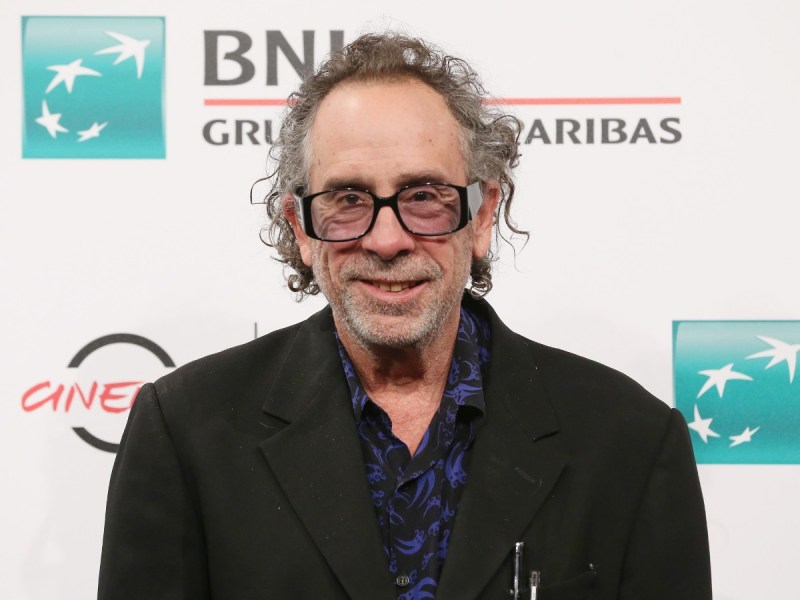 Tim Burton smiles in black blazer over dark blue shirt