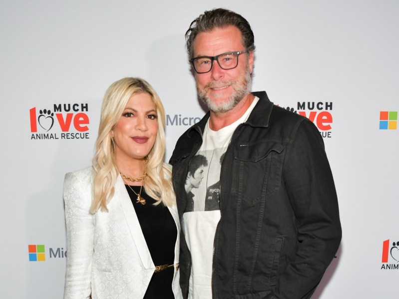 Tori Spelling (L) in black shirt and white jacket standing next to Dean McDermott, who is wearing a white shirt and black jacket