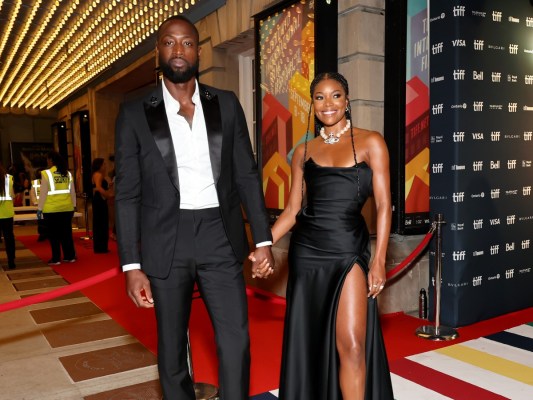 Dwayne Wade (L) in black suit holding hands with Gabrielle Union, who is wearing a black gown