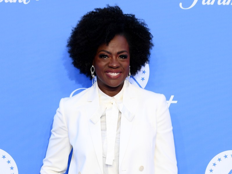 Viola Davis smiles in white pantsuit against blue backdrop