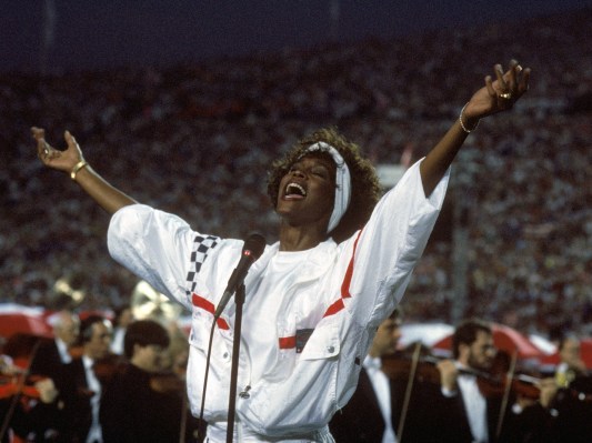 Whitney Houston wearing white track jacket and performing at 1991 Super Bowl