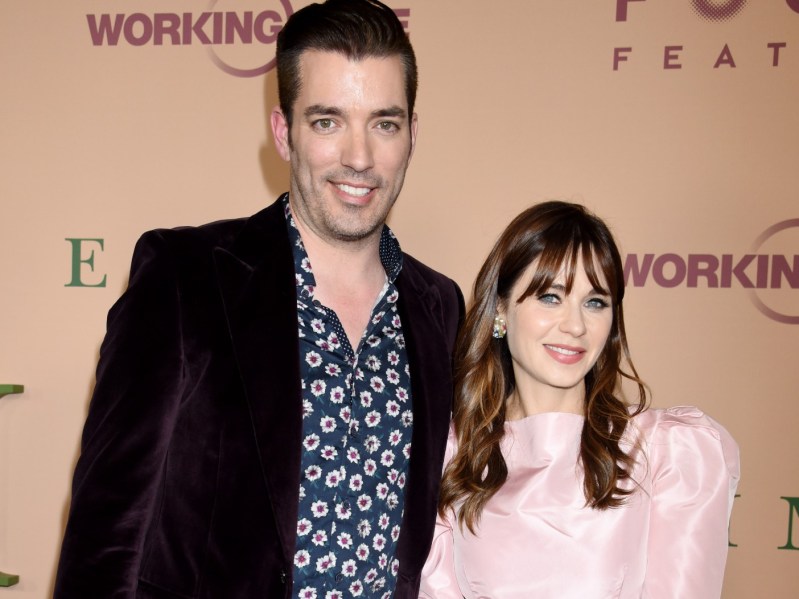 Zooey Deschanel (R) in pale pink dress standing next to Jonathan Scott, who is dressed in a patterned dress shirt and blazer