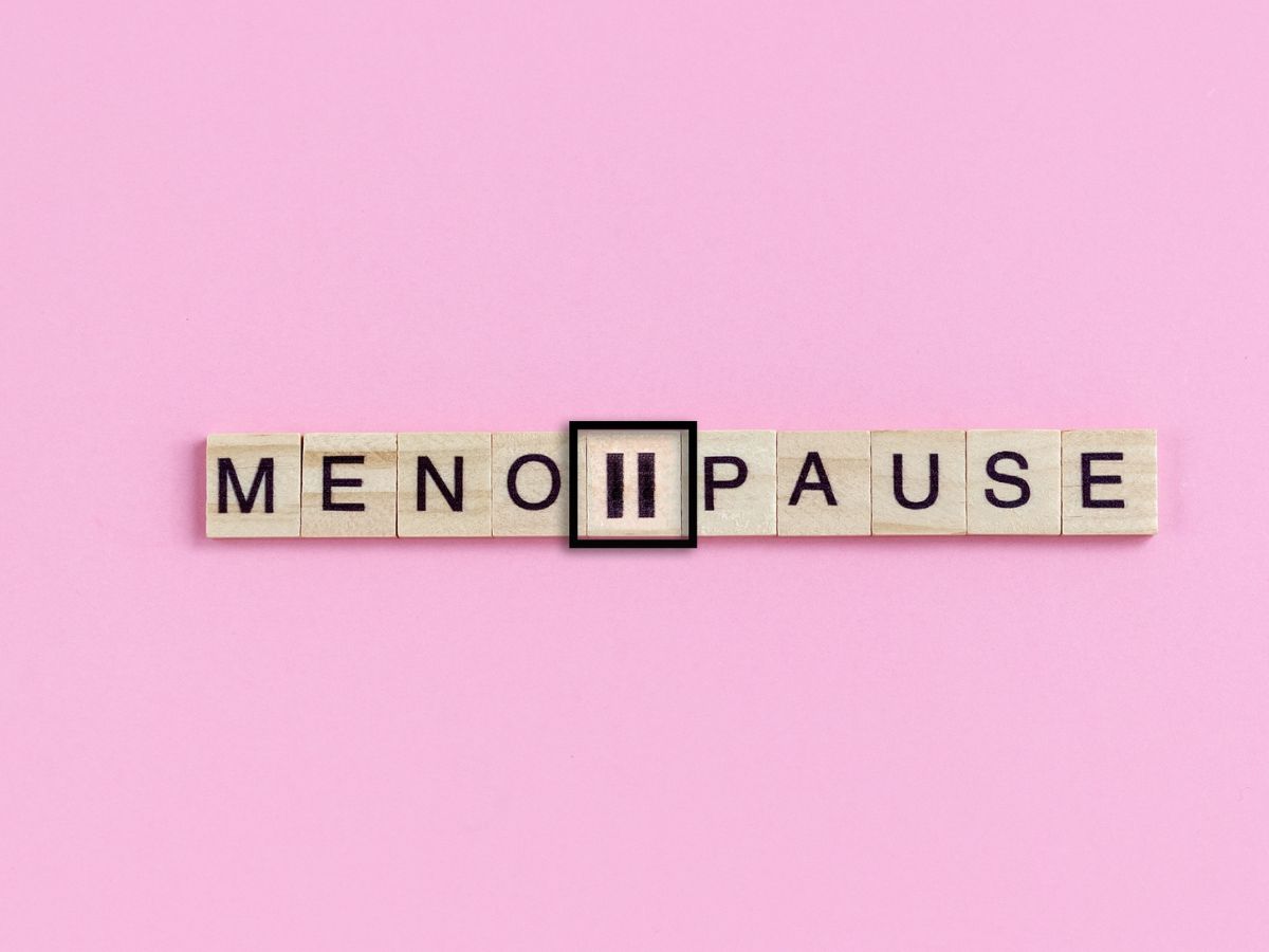 Scrabble letters spelling out "Menopause" with pause symbol in the middle