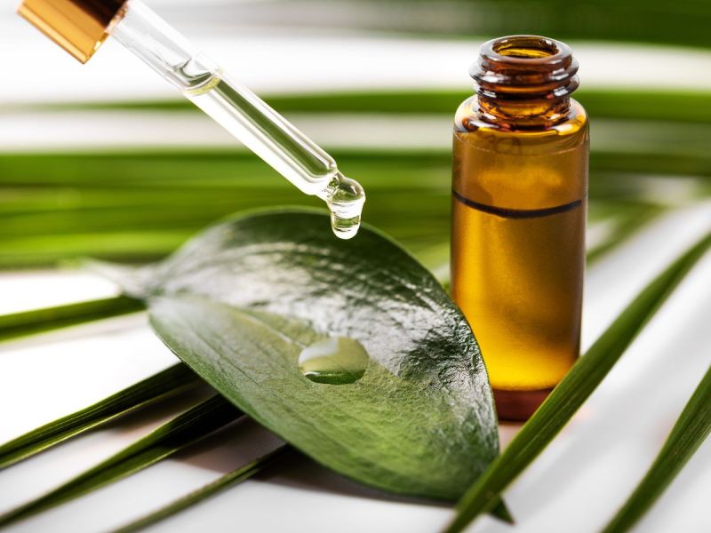 Skincare oil bottle and dropper dripping oil on leaf