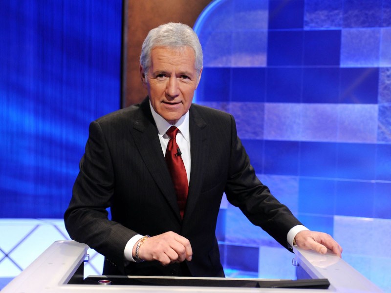 Alex Trebek in a black suit on the set of Jeopardy! in 2010