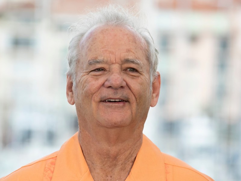 Bill Murray smiles in orange polo shirt
