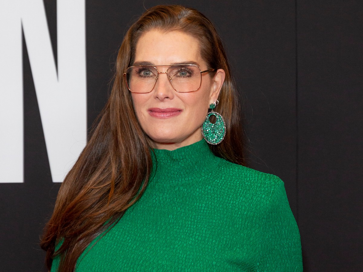 Brooke Shields smiles in green top with matching hoop earrings
