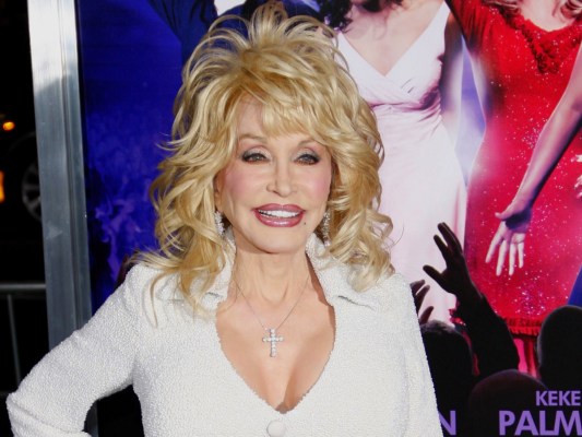 Dolly Parton smiles in white dress in a closeup photo