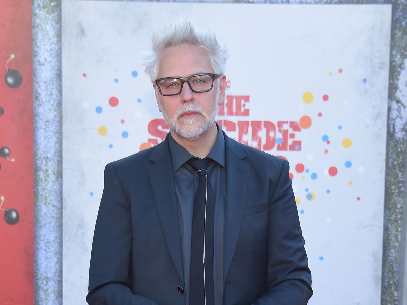 James Gunn in a blue suit with white hair and beard