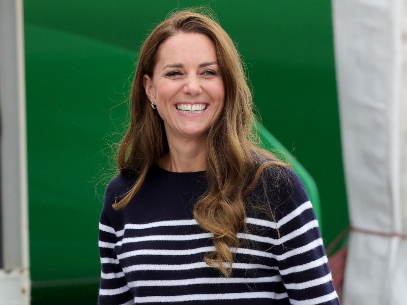 Kate Middleton smiles in navy and white striped sweater against green backdrop