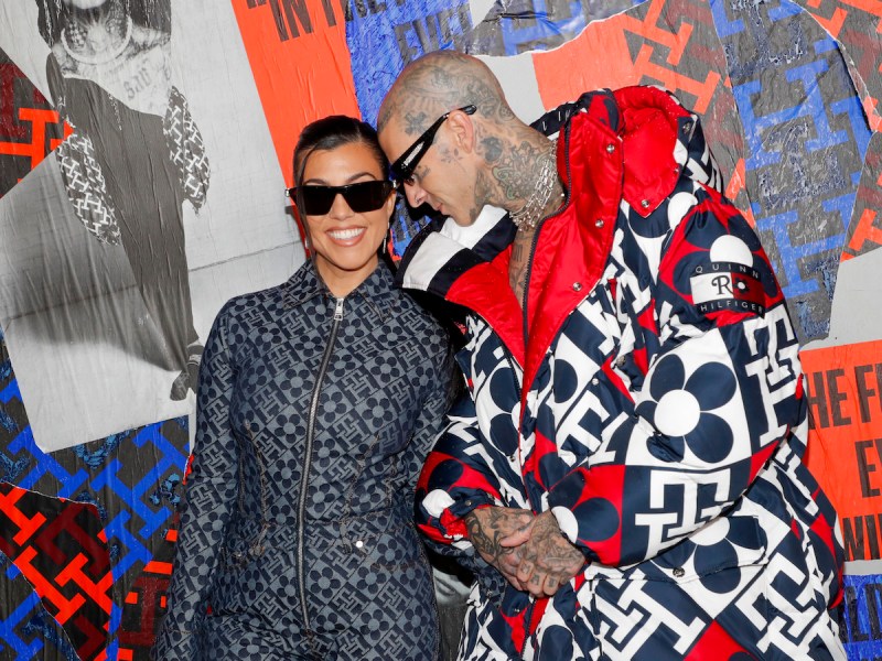 Kourtney Kardashian in a blue jumpsuit with Travis Barker in a black and white coat