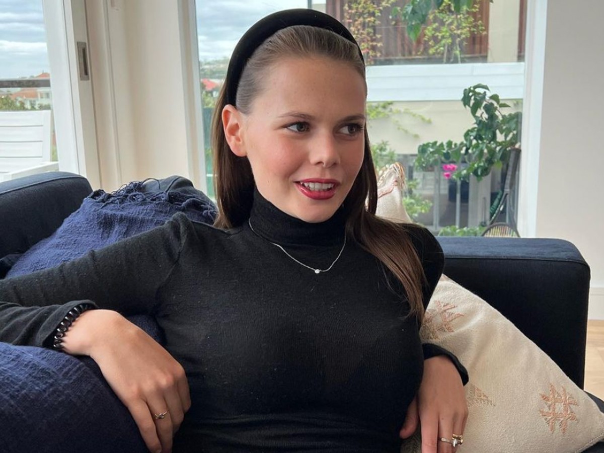 Lucia Hawley sits in chair wearing black sweater and black headband