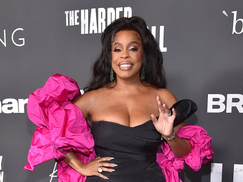 Niecy Nash smiling in a black dress and pink shawl