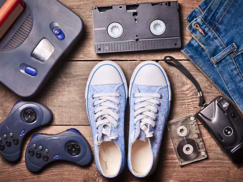 stock photo of '90s nostalgic items including a video game console, VHS tape, jeans, canvas shoes, and a cassette