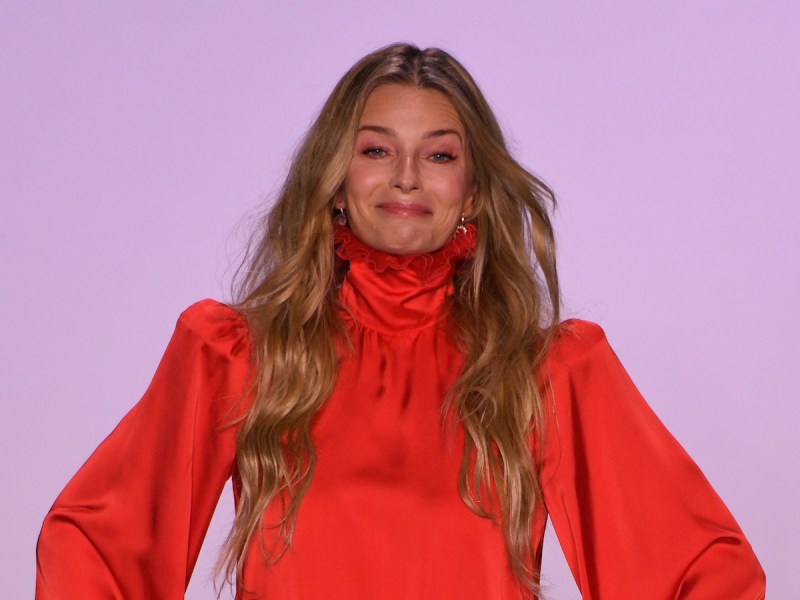 Paulina Porizkova smiling in an orange dress