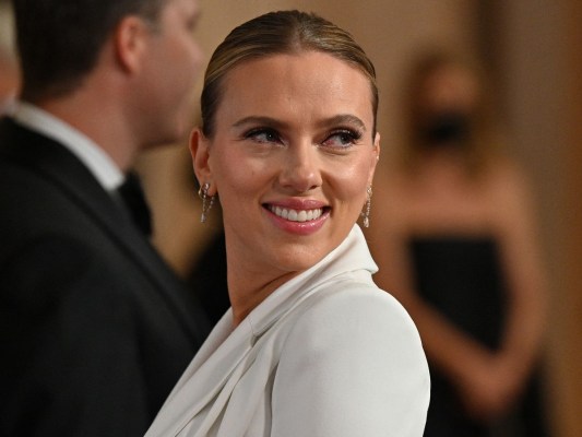Scarlett Johansson smiles over her shoulder while wearing white top