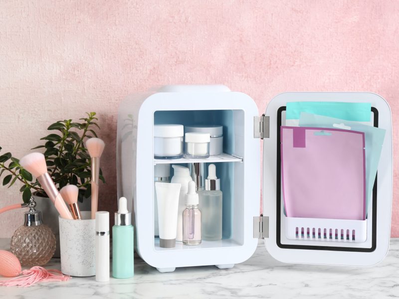 Open white cosmetics fridge with skin care products