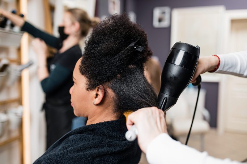 Black woman at salon getting a hair straightening treatment