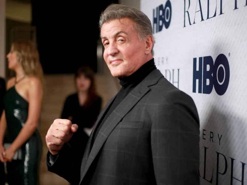 Sylvester Stallone smiling in a grey suit