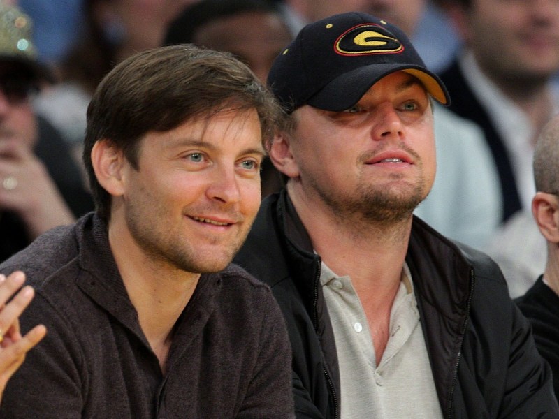 Tobey Maguire (L) and Leonardo DiCaprio smiling at sporting event in stands