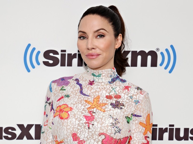 Whitney Cummings smiles in white turtleneck with colorful floral print