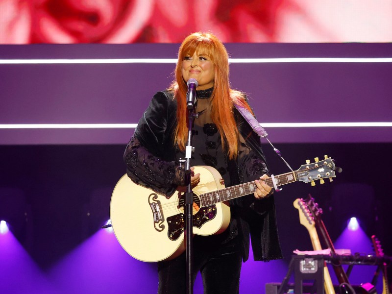 Wynonna Judd smiling and performing on stage at the CMAs