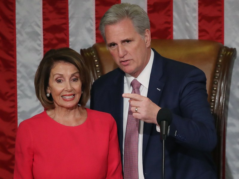 Nancy Pelosi in red on the left, Kevin Mccarthy in a blue suit on the right, pointing.