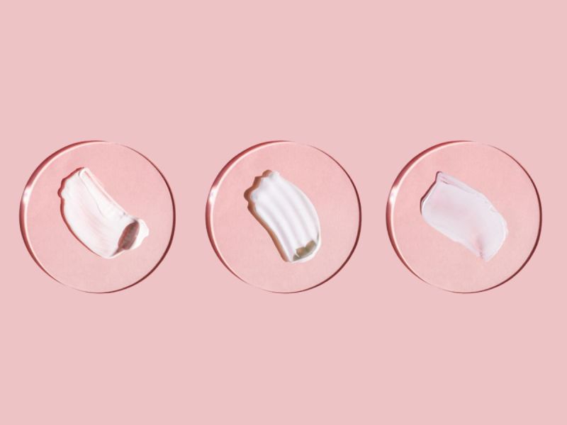 Dollops of three different skincare products under bubbles on pink background