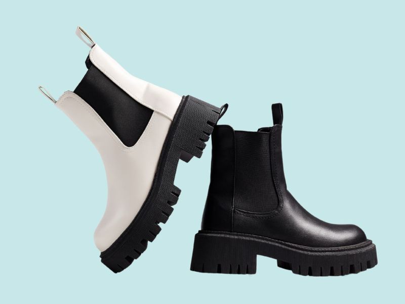 A white and black Chelsea lug sole boots on a blue background