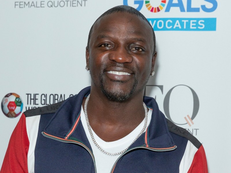 Akon smiles in red, white, and blue jacket against white backdrop